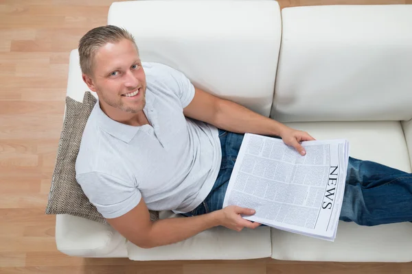 Homem no sofá com jornal — Fotografia de Stock