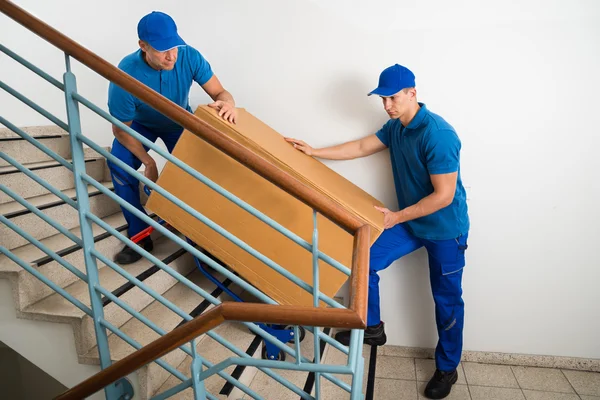 Двое мужчин с коробкой на лестнице — стоковое фото