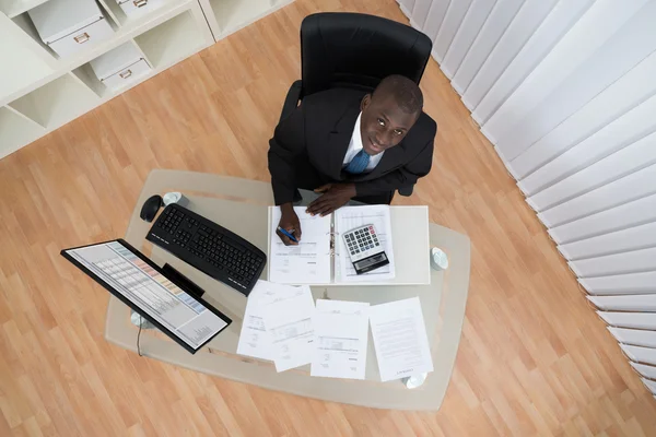 Businessman Calculating Bills In Office — Stock Photo, Image