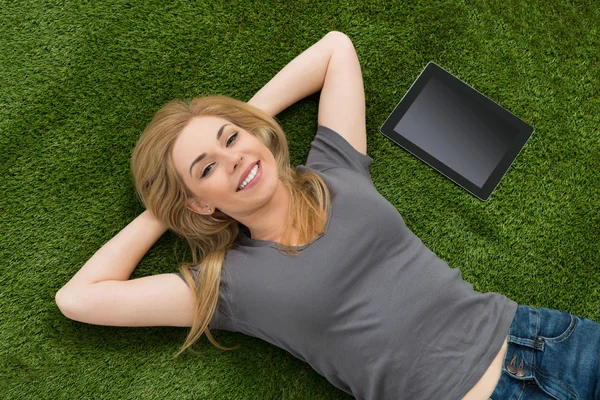 Femme couché avec tablette numérique sur herbe verte — Photo