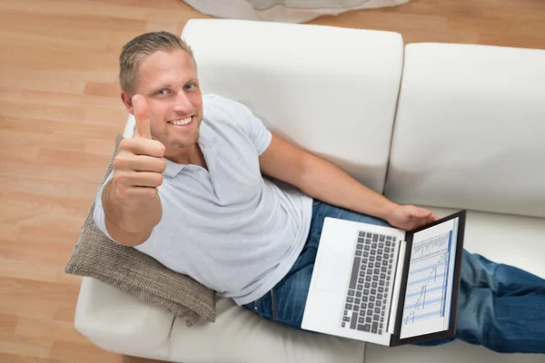 Mann zeigt Daumen nach oben, während er am Laptop arbeitet — Stockfoto