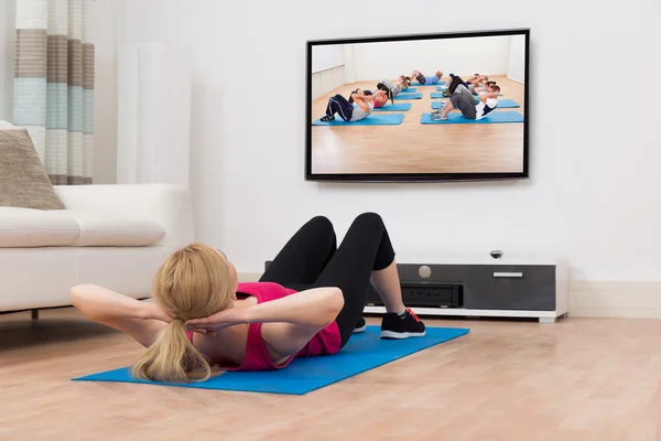 Vrouw uitoefenen tijdens het kijken naar televisie — Stockfoto