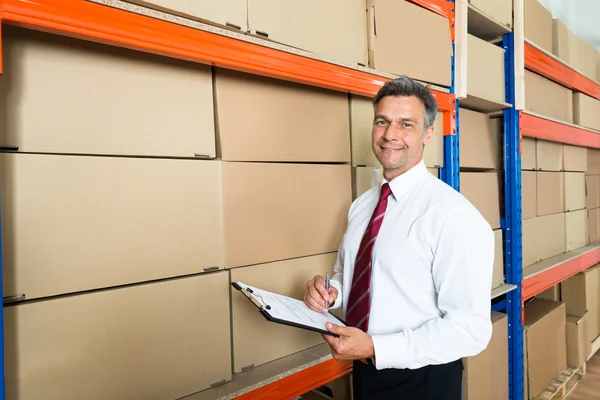 Gerente com área de transferência no armazém de distribuição — Fotografia de Stock