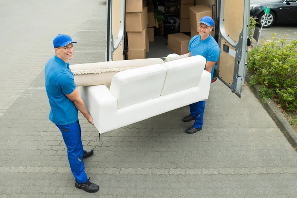 Рабочие кладут мебель и коробки в грузовик — стоковое фото
