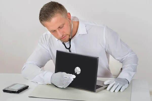 Technicien examinant l'ordinateur portable avec le stéthoscope — Photo