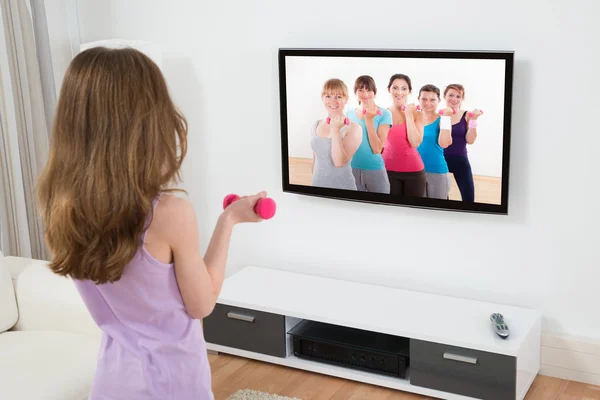 Girl With Dumbbell In Front Of Television — Stock Photo, Image