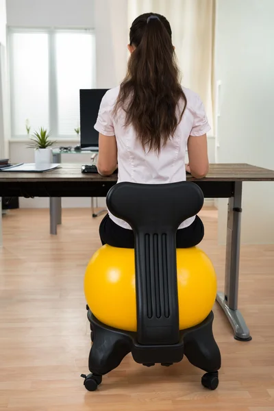 Femme d'affaires assis sur la balle de remise en forme dans le bureau — Photo