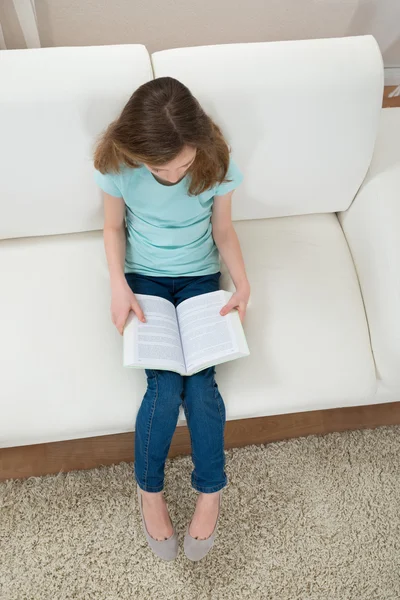 Tjej på soffan läsa bok — Stockfoto