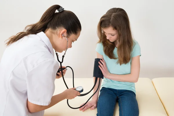 Médico verificando a pressão arterial da menina — Fotografia de Stock