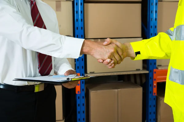Бизнесмен и складской рабочий пожимают руки — стоковое фото