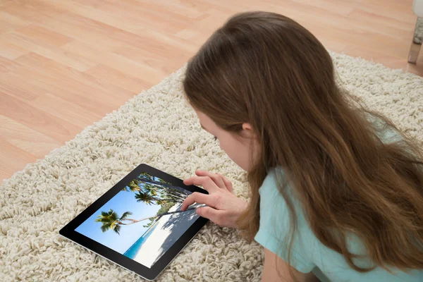 Ragazza sul tappeto guardando tavoletta digitale — Foto Stock