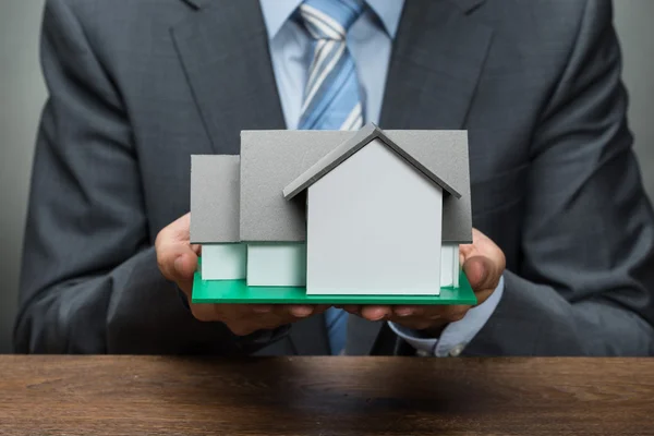 Zakenman holding house model — Stockfoto