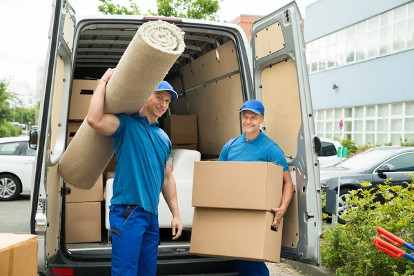 Arbeiter tragen Teppich und Kartons — Stockfoto