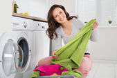 Frau wäscht Kleidung in Waschmaschine