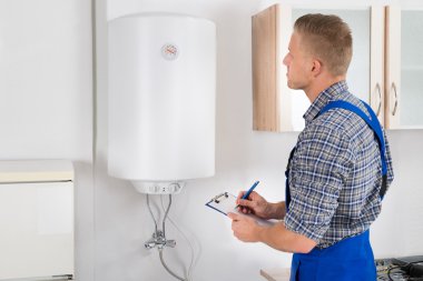 Man With Clipboard While Looking At Electric Boiler clipart