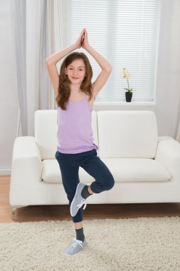Kız evde yoga yapıyor.