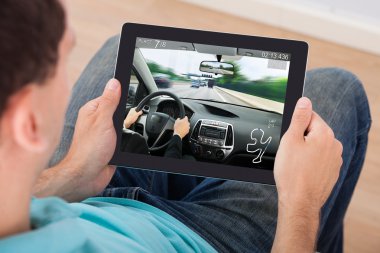 Dijital Tablet üzerinde araba oyunu oynayan adam