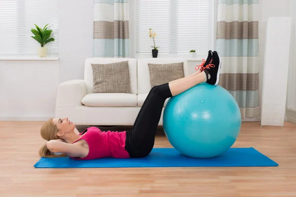 Vrouw uitoefenend met Fitness bal In woonkamer — Stockfoto