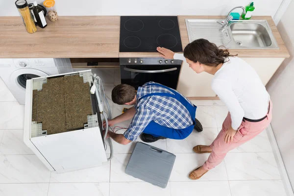 Kvinna som tittar på den reparatör reparera diskmaskin — Stockfoto