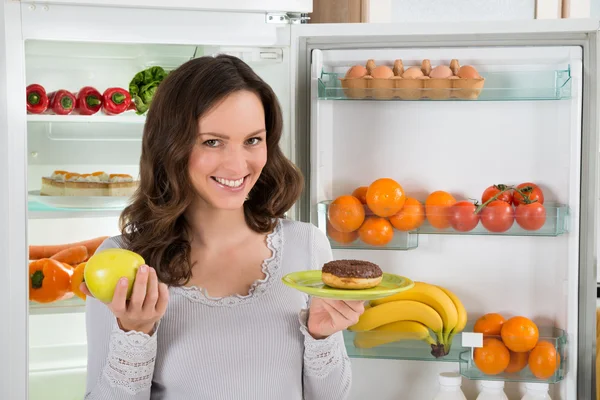 Mujer sosteniendo verde manzana y donut — Foto de Stock