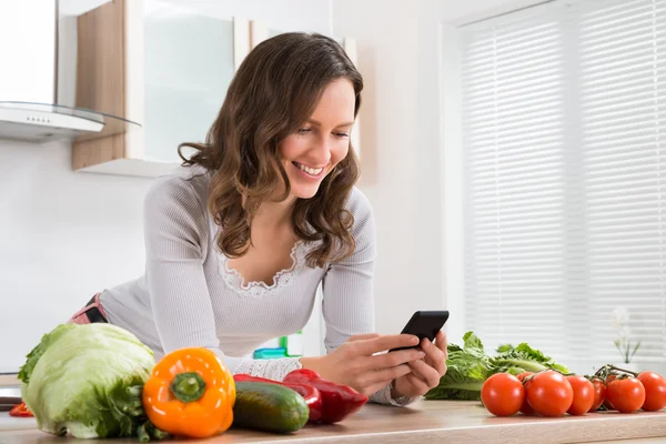 Mujer sonriendo mientras usa el teléfono móvil — Foto de Stock