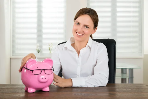 Mujer de negocios con Piggybank en el escritorio — Foto de Stock
