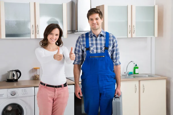 Kvinna med reparatör visar tummen upp tecken — Stockfoto