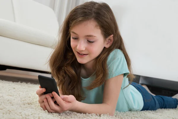 Ragazza con telefono cellulare in salotto — Foto Stock