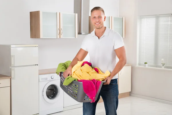 Homem transportando cesta de lavanderia na sala de cozinha — Fotografia de Stock