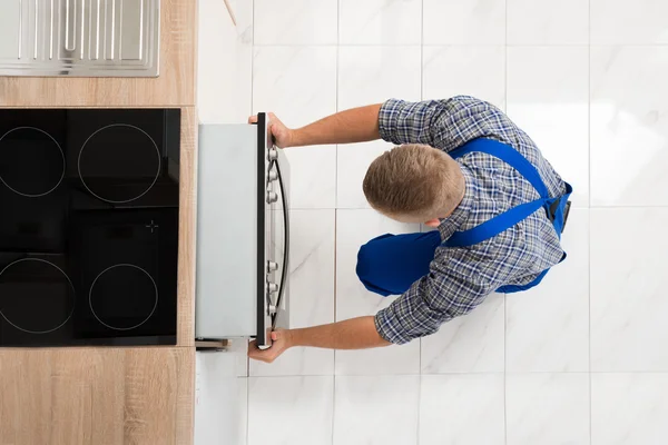 Чоловік ремонтує кухонну піч — стокове фото