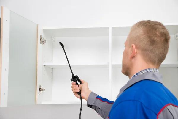 Worker Spraying Insecticide On Shelf — Stock Photo, Image