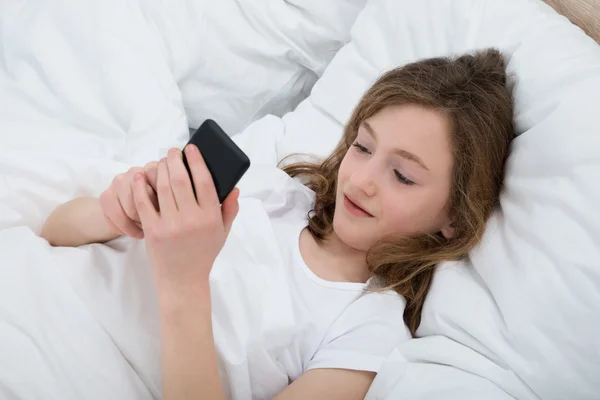 Chica con teléfono móvil en el dormitorio —  Fotos de Stock