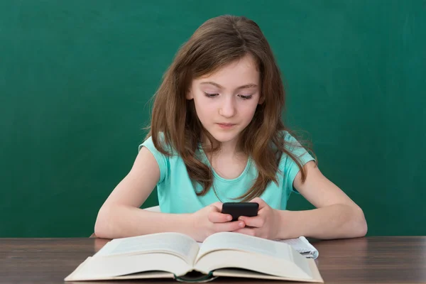 Ragazza con cellulare e libri — Foto Stock