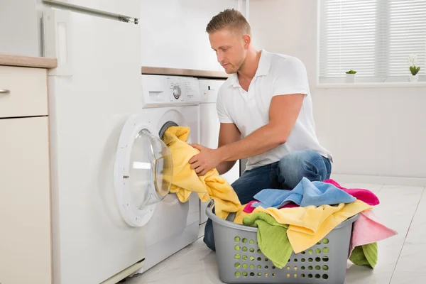 Hombre poniendo ropa sucia en la lavadora — Foto de Stock