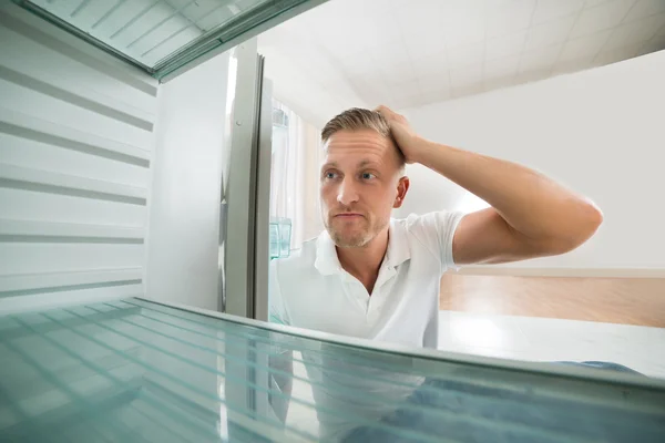 Человек, смотрящий в пустой холодильник — стоковое фото