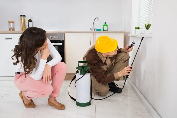 Donna guardando operaio spruzzatura insetticida — Foto Stock