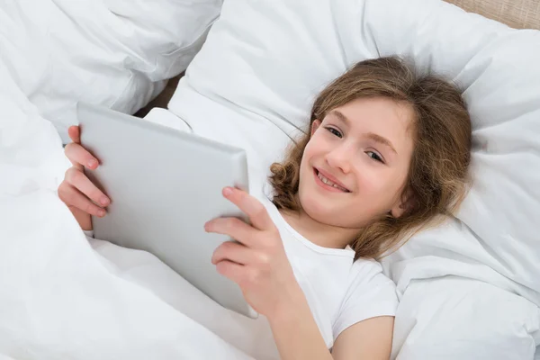 Menina na cama com tablet digital — Fotografia de Stock