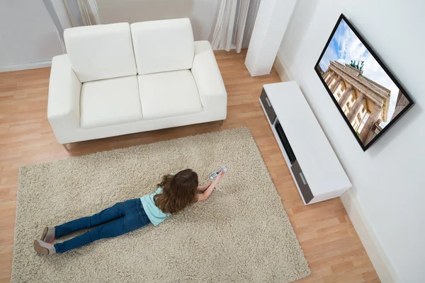 Menina no tapete assistindo televisão — Fotografia de Stock