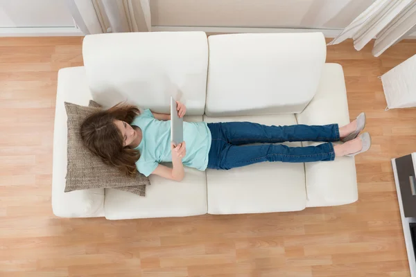 Meisje op Sofa met behulp van digitale Tablet — Stockfoto