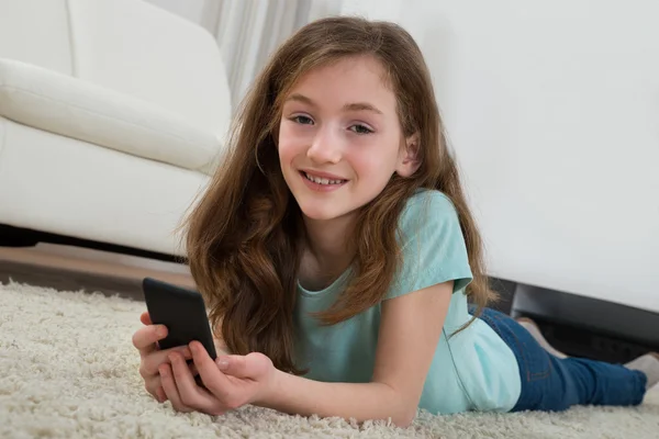 Dívka s mobilním telefonem v obývacím pokoji — Stock fotografie