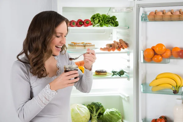 冷蔵庫の前で食べる女 — ストック写真