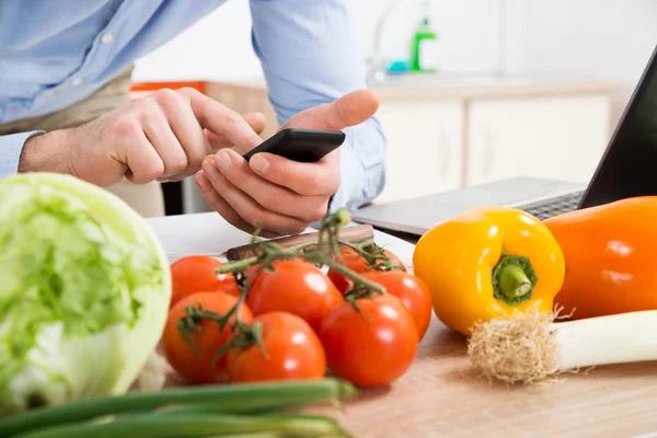 Person mit Handy in der Küche — Stockfoto