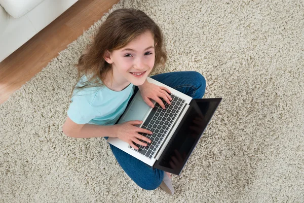 Fille assise sur le tapis avec ordinateur portable — Photo