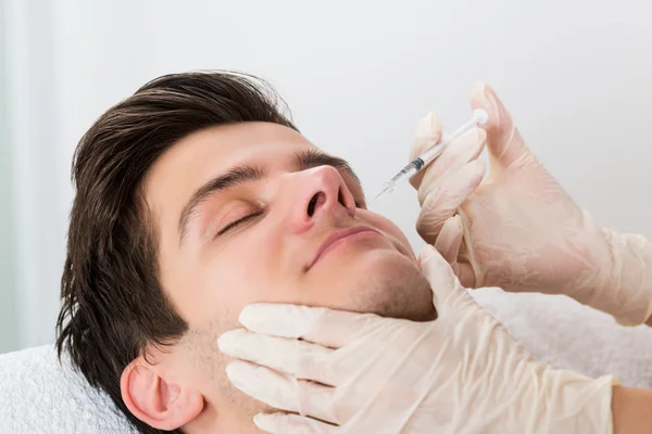 Médico dando injeção no rosto do homem — Fotografia de Stock