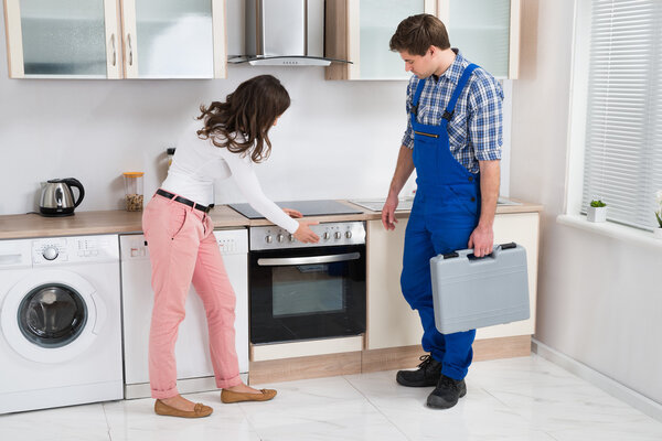 Housewife Showing Damaged Oven To Worker