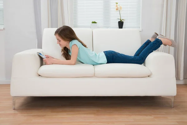 Meisje op Sofa kijken naar digitale Tablet — Stockfoto