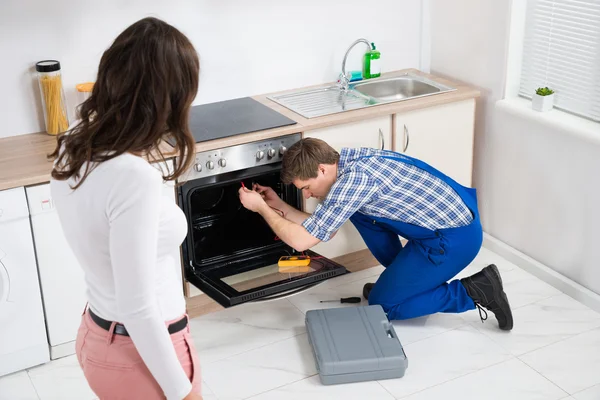 Woman Looking At Worker Repairing Oven — Stock Photo, Image