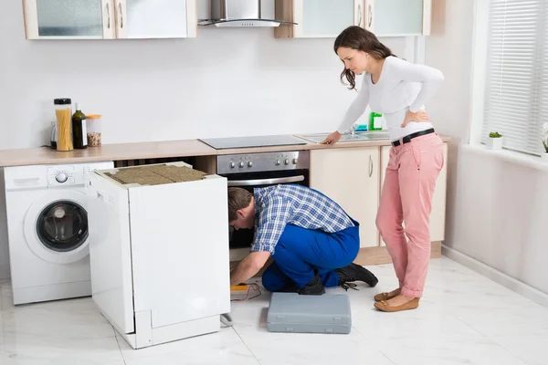 Donna guardando il riparatore riparazione lavastoviglie — Foto Stock