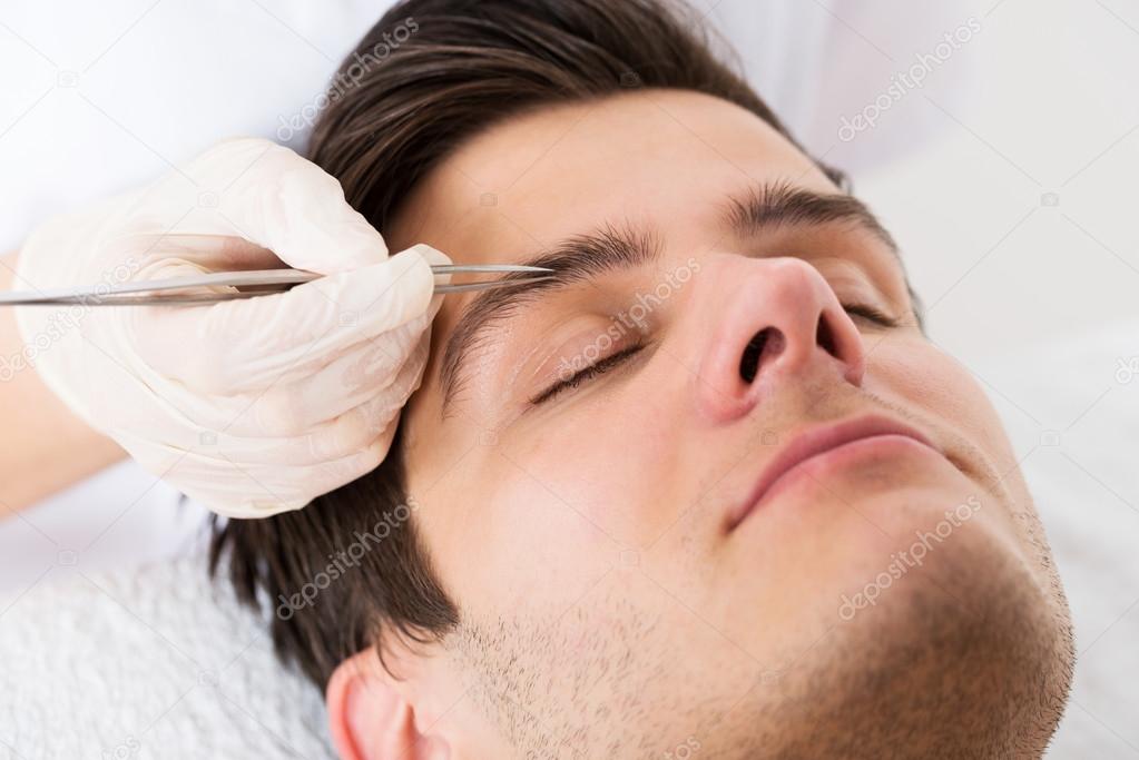 Beautician Hands Plucking Man Eyebrows With Tweezers