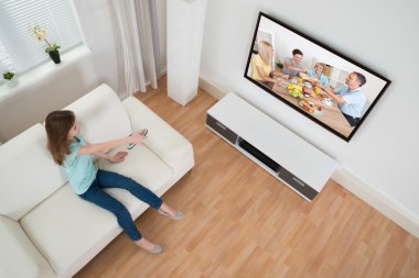 Uzaktan kumanda televizyon önünde tutan kız
